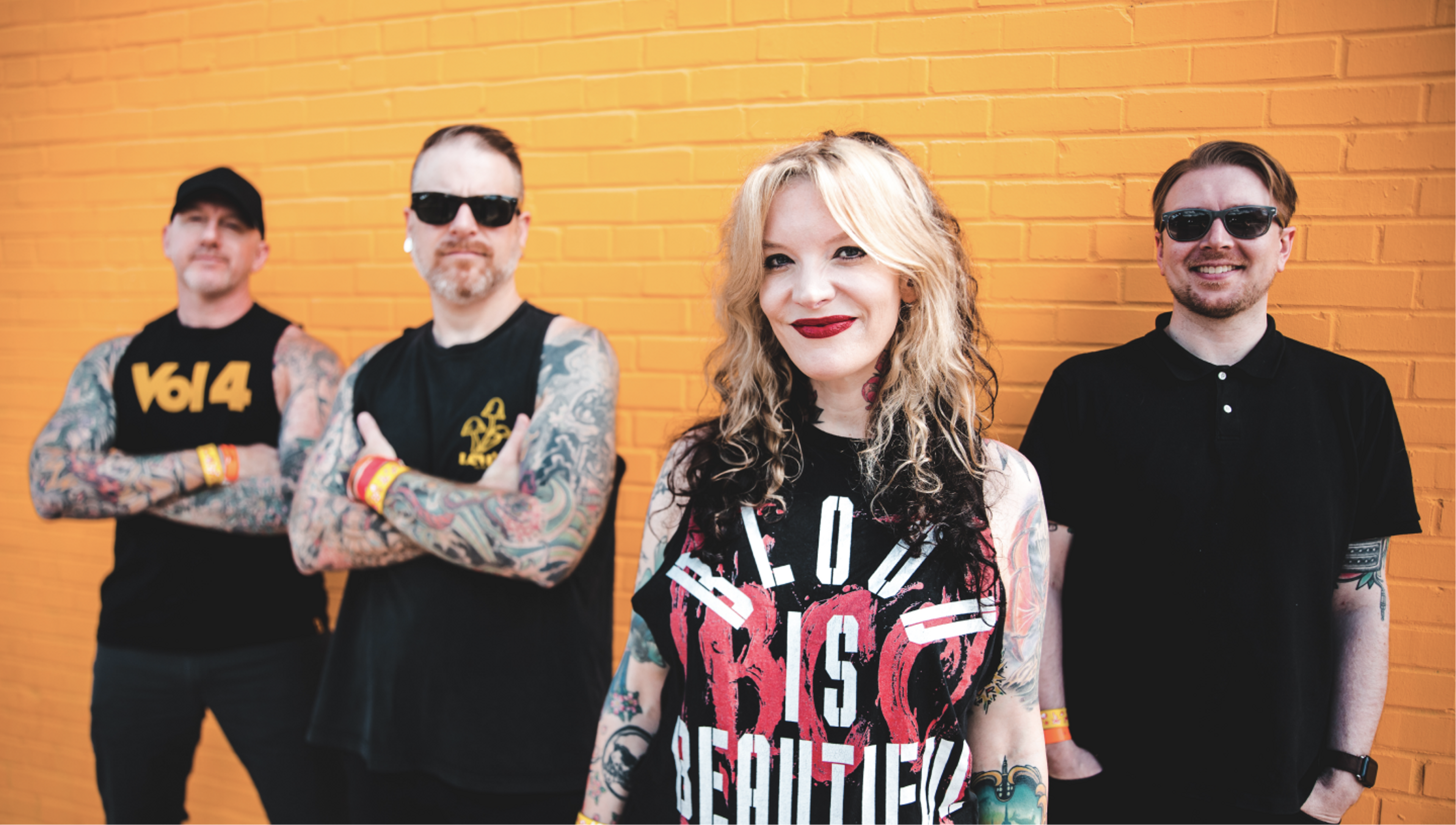 Band members standing against yellow brick wall